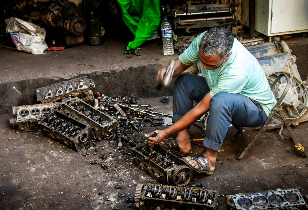Mecânico inspecionando o motor de um carro com capô aberto em uma oficina