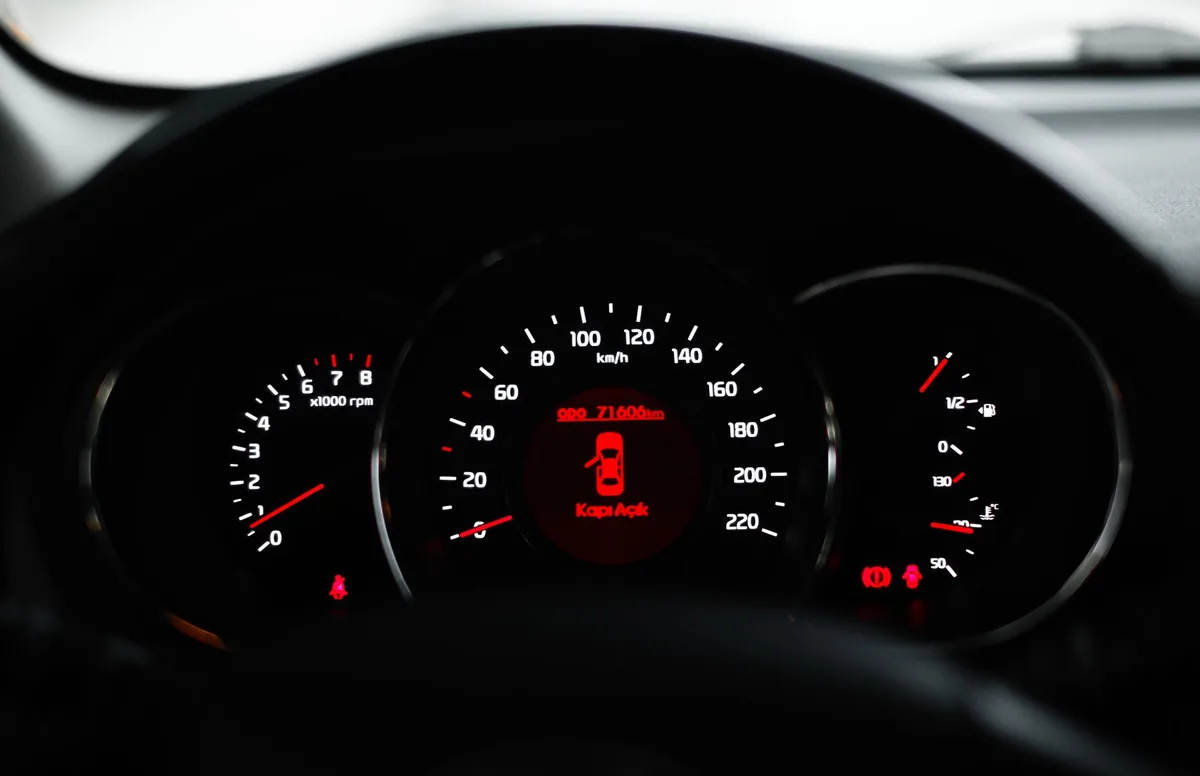 Painel de carro em close com luzes de aviso acesas.